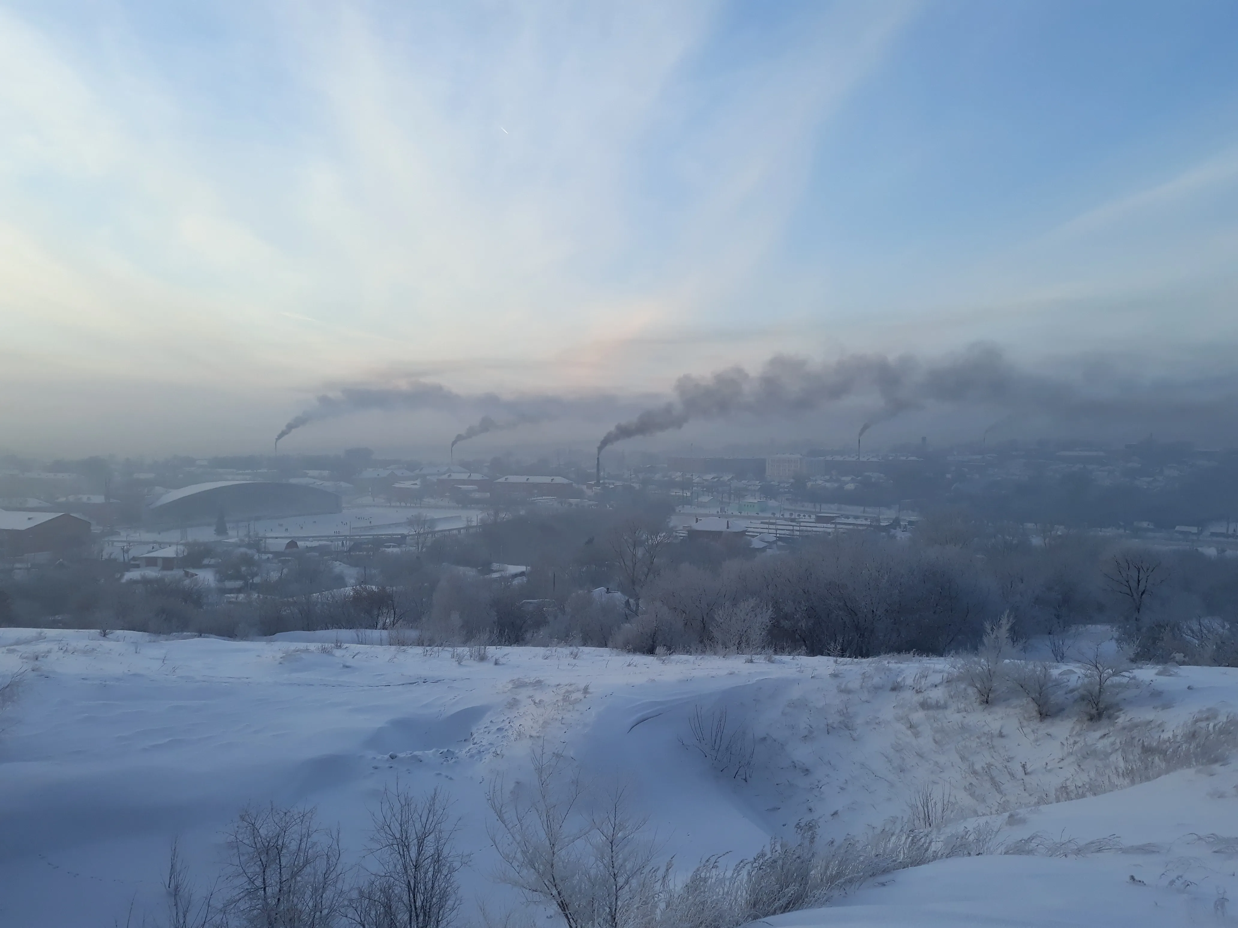 Панорама зимнего Киселёвска с несколькими видимыми шлейфами над городом